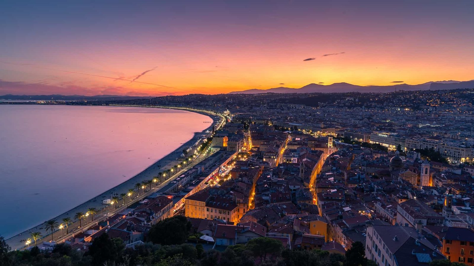 A photo of Nice, France, at sunset. The city is lit up and looks beautiful