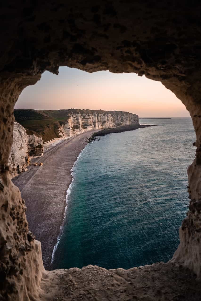 A scenic view of a beach and cliffs from inside a cave