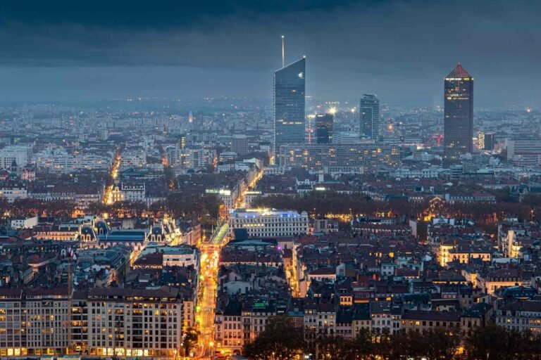 A photo of Lyon, France, at night. The city is lit up with many lights, and there are tall buildings