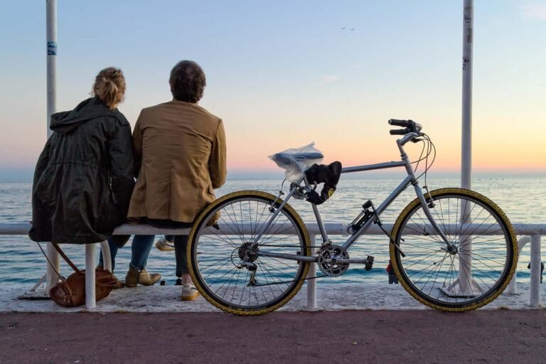 A picture of a man and a woman sitting at a place and watching the sunset together on a beachside