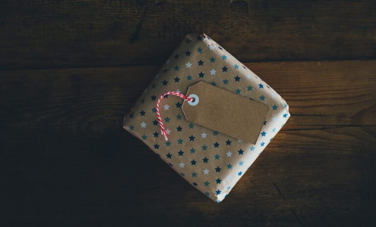 A wrapped gift with a brown paper tag on a wooden surface